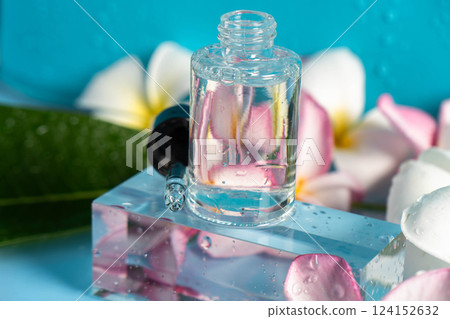 Hydration drops rest on a crystal surface next to soft plumeria blooms, evoking a spa vibe. 124152632