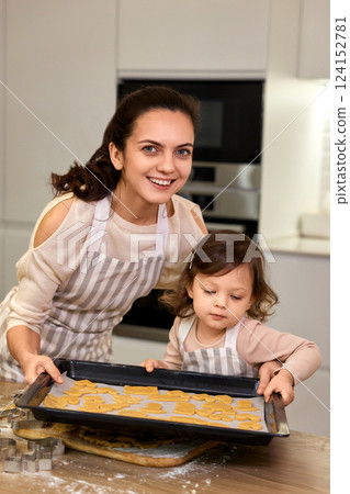 happy mother and little child daughter holding tray with gingerbread cookies in kitchen happy mother and little child daughter holding tray with gingerbread cookies in kitchen 124152781