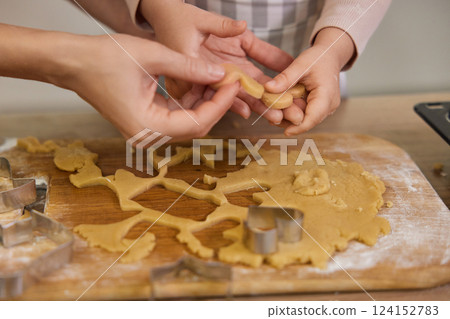 close-up, hands of mother and little child cutting cookies of raw gingerbread dough in kitchen, Christmas traditions 124152783