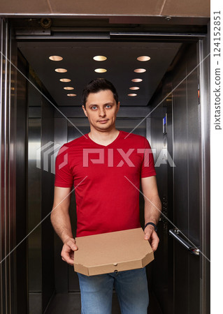 Deliveryman holding pizza box in elevator, food delivery to your home. Deliveryman holding pizza box in elevator, food delivery to your home. 124152851