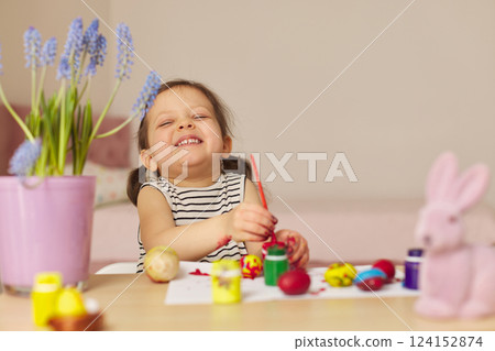 Little child girl paint Easter eggs at home. kid is preparing for Easter. 124152874