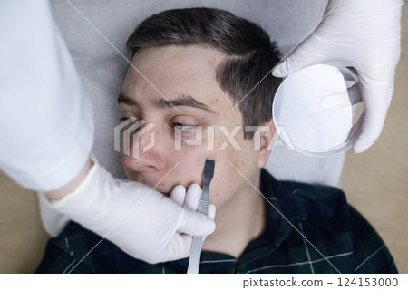 A dermatologist takes a skin scraping and tests for demodicosis and dermatitis, fungal infection. Close-up of a male patient's face at a doctor's appointment A dermatologist takes a skin scraping and tests for demodicosis and dermatitis, fungal infection. Close-up of a male patient's face at a doctor's appointment 124153000