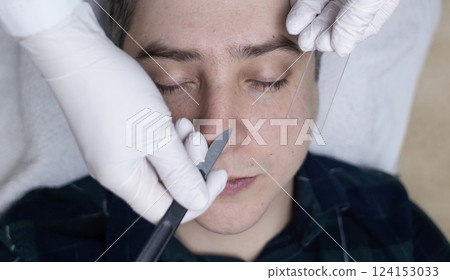 A dermatologist takes a skin scraping and tests for demodicosis and dermatitis, fungal infection. Close-up of a male patient's face at a doctor's appointment A dermatologist takes a skin scraping and tests for demodicosis and dermatitis, fungal infection. Close-up of a male patient's face at a doctor's appointment 124153033
