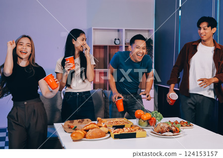 Happy young friends group having lunch at home. Asia family party eating pizza food and laughing enjoying meal while sitting at dining table together at house. Celebration holiday and togetherness. 124153157