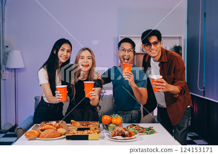 Happy young friends group having lunch at home. Asia family party eating pizza food and laughing enjoying meal while sitting at dining table together at house. Celebration holiday and togetherness. 124153171
