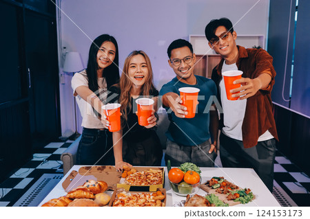 Happy young friends group having lunch at home. Asia family party eating pizza food and laughing enjoying meal while sitting at dining table together at house. Celebration holiday and togetherness. 124153173