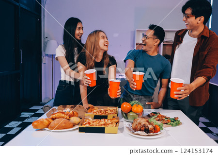 Happy young friends group having lunch at home. Asia family party eating pizza food and laughing enjoying meal while sitting at dining table together at house. Celebration holiday and togetherness. 124153174