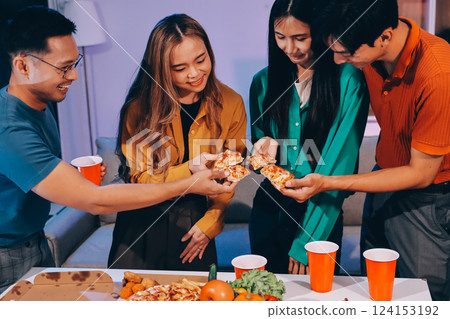 Happy young friends group having lunch at home. Asia family party eating pizza food and laughing enjoying meal while sitting at dining table together at house. Celebration holiday and togetherness. 124153192