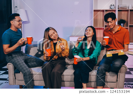 Happy young friends group having lunch at home. Asia family party eating pizza food and laughing enjoying meal while sitting at dining table together at house. Celebration holiday and togetherness. 124153194