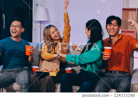 Happy young friends group having lunch at home. Asia family party eating pizza food and laughing enjoying meal while sitting at dining table together at house. Celebration holiday and togetherness. 124153198