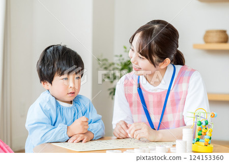 托兒所裡,一名女托兒所老師和一名男孩一起玩耍。 托兒所裡,一名女托兒所老師和一名男孩一起玩耍。 124153360