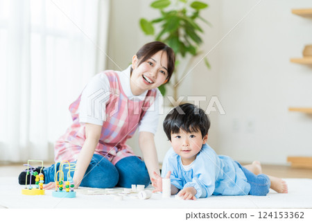 托兒所裡,一名女托兒所老師和一名男孩一起玩耍。 托兒所裡,一名女托兒所老師和一名男孩一起玩耍。 124153362