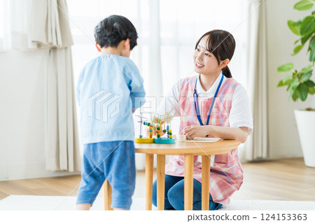 托兒所裡,一名女托兒所老師和一名男孩一起玩耍。 托兒所裡,一名女托兒所老師和一名男孩一起玩耍。 124153363