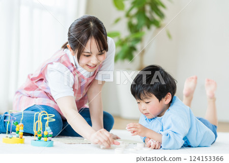 托兒所裡，一名女托兒所老師和一名男孩一起玩耍。 124153366