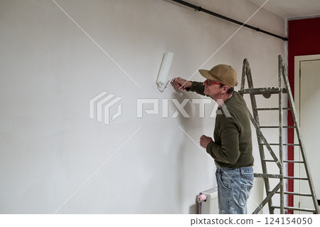 Painter in dirty clothes renovate a wall in a loft Painter in dirty clothes renovate a wall in a loft 124154050