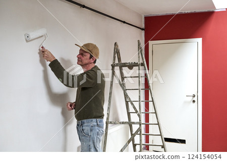 Painter in dirty clothes renovate a wall in a loft Painter in dirty clothes renovate a wall in a loft 124154054