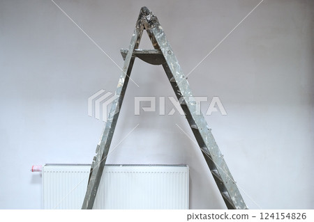 Dirty ladder in front on a white wall for renovation 124154826