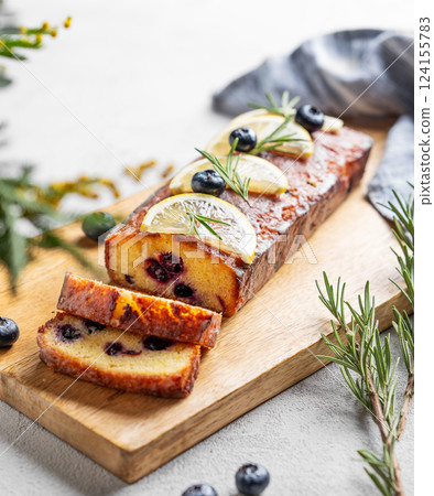 Lemon pie with sugar glaze, blueberries, decorated with rosemary and citrus slices on a wooden board 124155783