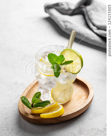 Cocktail or lemonade mojito with fresh lemon, lime, mint and ice on a wooden plate  124155805