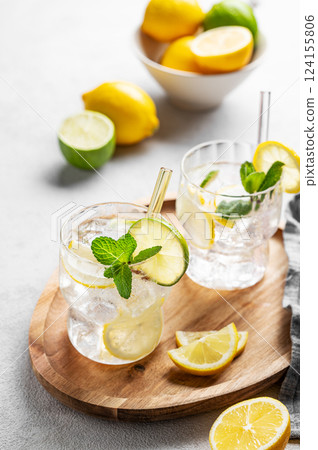 Cocktail or lemonade mojito with fresh lemon, lime, mint and ice on a wooden plate Cocktail or lemonade mojito with fresh lemon, lime, mint and ice on a wooden plate 124155806