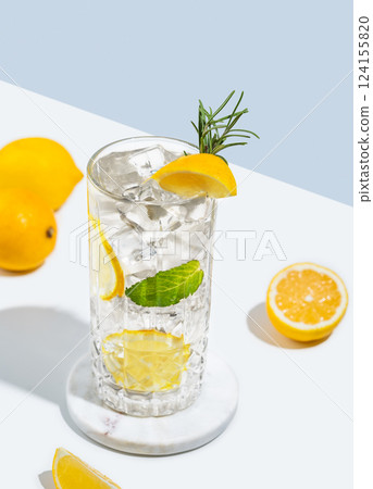 Mojito cocktail with lemon, rosemary and ice in a glass on a white blue background with fruits. Mojito cocktail with lemon, rosemary and ice in a glass on a white blue background with fruits. 124155820