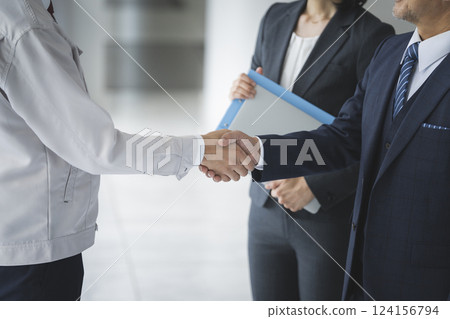 商業形象：一位穿西裝的商人和一位穿著工作服的男士握手 124156794
