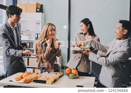 Asian office colleagues and friends enjoy a daytime BBQ with pizza and beer, celebrating Halloween and cheering for their favorite soccer team, creating a lively atmosphere filled with joy. 124156888