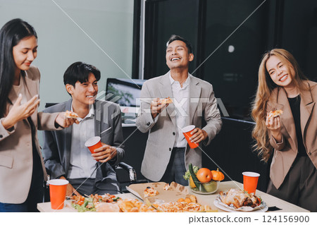 Asian office colleagues and friends enjoy a daytime BBQ with pizza and beer, celebrating Halloween and cheering for their favorite soccer team, creating a lively atmosphere filled with joy. 124156900