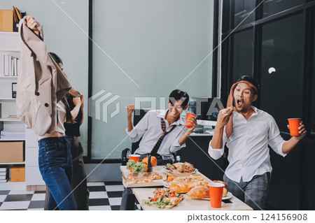 Asian office colleagues and friends enjoy a daytime BBQ with pizza and beer, celebrating Halloween and cheering for their favorite soccer team, creating a lively atmosphere filled with joy. 124156908