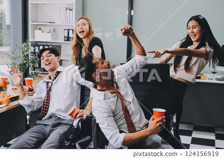 Asian office colleagues and friends enjoy a daytime BBQ with pizza and beer, celebrating Halloween and cheering for their favorite soccer team, creating a lively atmosphere filled with joy. 124156919