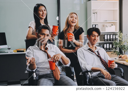 Asian office colleagues and friends enjoy a daytime BBQ with pizza and beer, celebrating Halloween and cheering for their favorite soccer team, creating a lively atmosphere filled with joy. 124156922