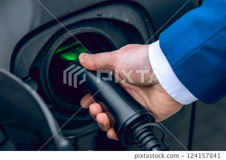 Man at gas station holding nozzle refueling his car with unleaded petrol Man at gas station holding nozzle refueling his car with unleaded petrol 124157841