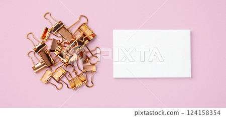 Rose gold binder clips and memo note paper on pastel pink background 124158354
