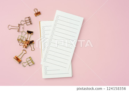 To do list paper with gold binder clip on pink background, top view 124158356