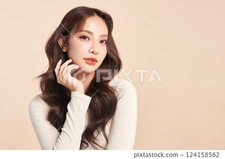 A beautiful young Asian woman with clean, fresh skin against a beige background. Skincare, facial treatment, cosmetology, beauty, and spa. An elegant portrait of an Asian woman. 124158562