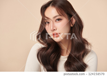 A beautiful young Asian woman with clean, fresh skin against a beige background. Skincare, facial treatment, cosmetology, beauty, and spa. An elegant portrait of an Asian woman. 124158570
