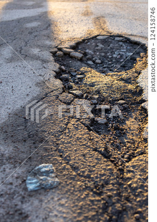 potholes in the road, holes in the asphalt on the roadway or highway.  124158746