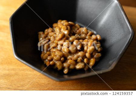 Sticky stringy natto in a black bowl on a wooden table background 124159357