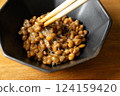 在木桌背景上，用筷子攪拌納豆，在黑色碗中形成黏稠的細絲 124159420