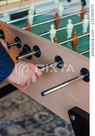 Close-up of a hand playing foosball, gripping the handle during a game match. High quality photo Close-up of a hand playing foosball, gripping the handle during a game match. High quality photo 124160973