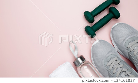 Gray sports shoes, green dumbbells, water bottle, and white towel on a pastel pink background. Fitness and healthy lifestyle concept Gray sports shoes, green dumbbells, water bottle, and white towel on a pastel pink background. Fitness and healthy lifestyle concept 124161837
