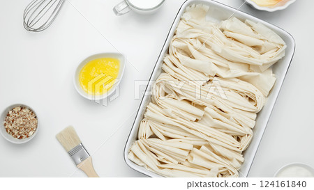 Filo dough in a baking dish next to Crinkle Cake butter for greasing Filo dough in a baking dish next to Crinkle Cake butter for greasing 124161840
