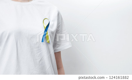 Symbolizing World Down Syndrome Day. A person wearing a white t-shirt with a yellow and blue awareness ribbon Symbolizing World Down Syndrome Day. A person wearing a white t-shirt with a yellow and blue awareness ribbon 124161882
