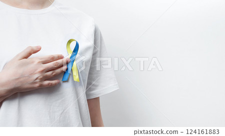 Symbolizing World Down Syndrome Day. A person wearing a white t-shirt with a yellow and blue awareness ribbon 124161883