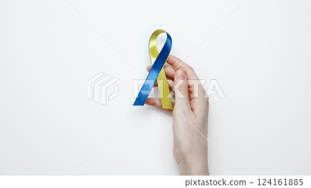 Symbolizing World Down Syndrome Day. A person holds a yellow and blue awareness ribbon 124161885