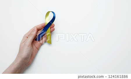 Symbolizing World Down Syndrome Day. A person holds a yellow and blue awareness ribbon 124161886