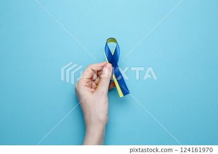 A person holds a yellow and blue awareness ribbon, symbolizing World Down Syndrome Day 124161970