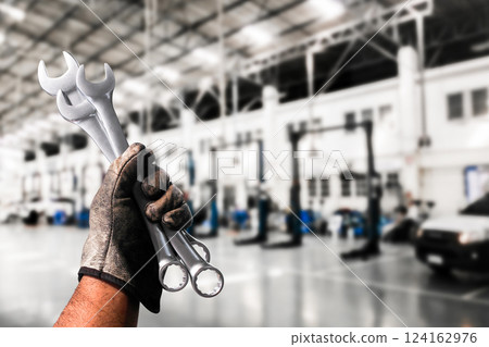 Mechanic holding wrenches in automotive workshop , Slim Open-end Wrench in  mechanic hand 124162976