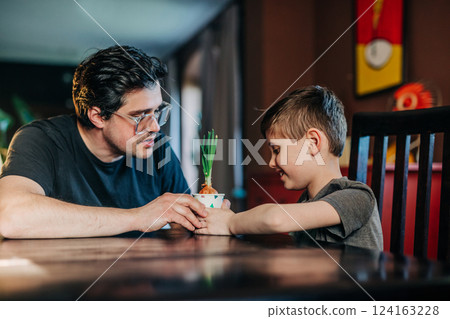 father teaches his son how to grow onions in a paper cup father teaches his son how to grow onions in a paper cup 124163228
