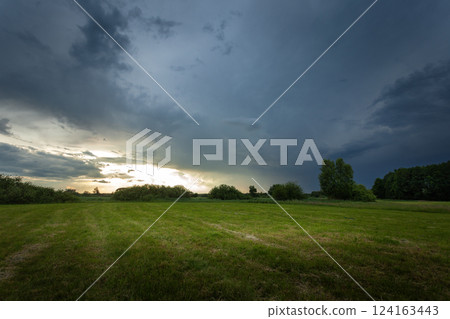 A dark rain cloud over a green meadow A dark rain cloud over a green meadow 124163443
